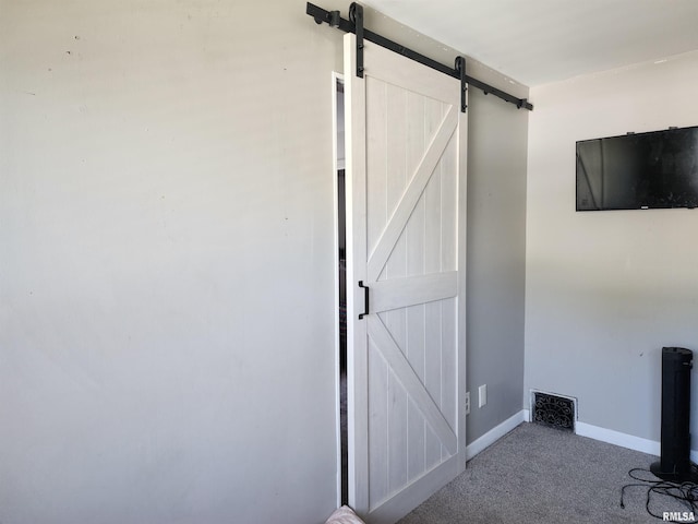 unfurnished office with a barn door, carpet, and baseboards