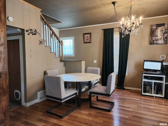 dining area with ornamental molding, a chandelier, wood finished floors, baseboards, and stairs