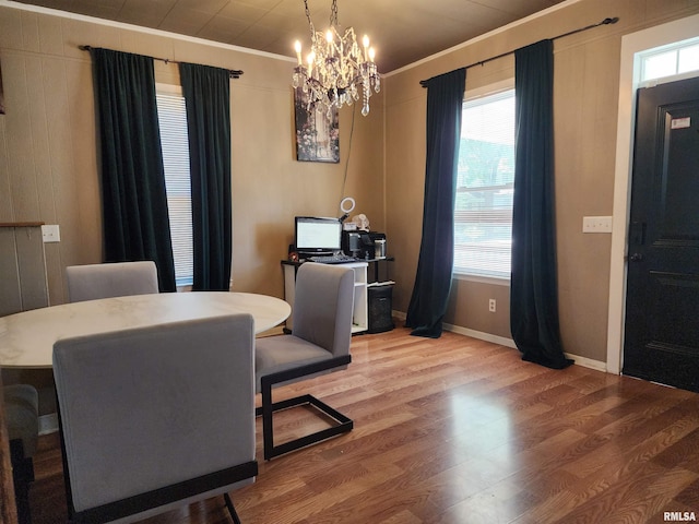 dining space with ornamental molding, healthy amount of natural light, a chandelier, wood finished floors, and baseboards