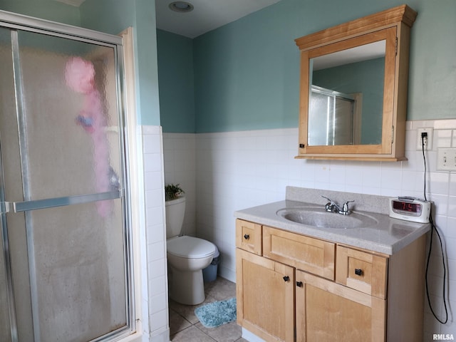 bathroom with tile walls, a stall shower, vanity, toilet, and wainscoting