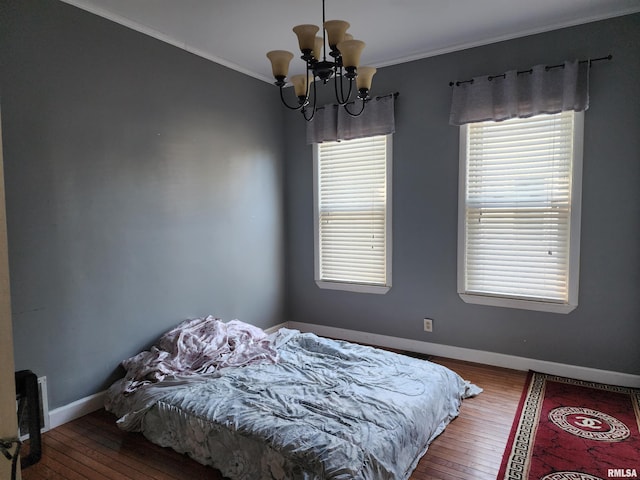 bedroom with a chandelier, hardwood / wood-style flooring, ornamental molding, and baseboards
