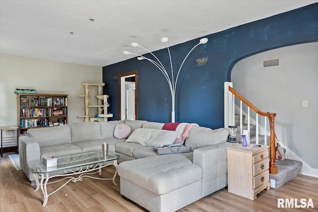 living area with wood finished floors, stairway, and arched walkways