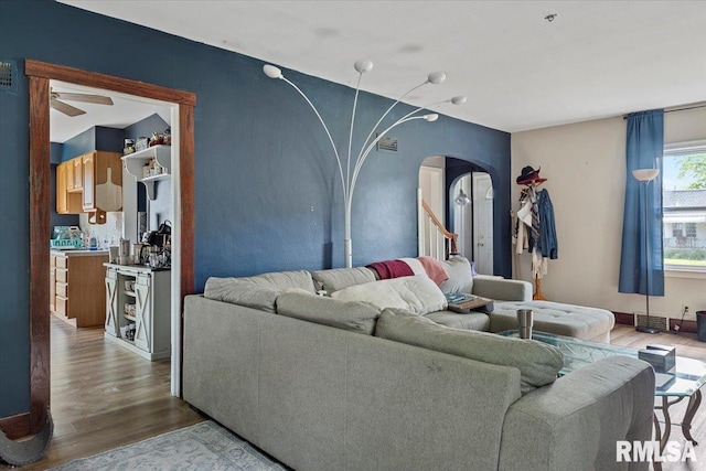 living room featuring arched walkways, wood finished floors, and ceiling fan