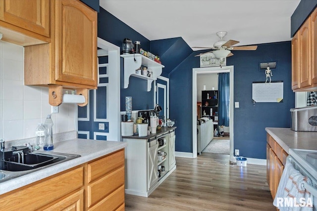kitchen with a ceiling fan, white range with electric cooktop, light wood-style flooring, tasteful backsplash, and a sink