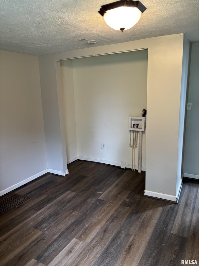 unfurnished room with dark wood-style flooring, a textured ceiling, and baseboards