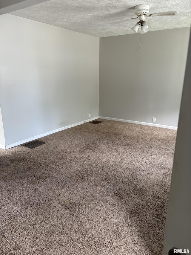 carpeted empty room with a textured ceiling, ceiling fan, and baseboards