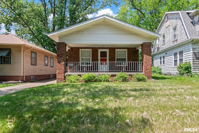 view of front facade with a porch, a front lawn, and brick siding