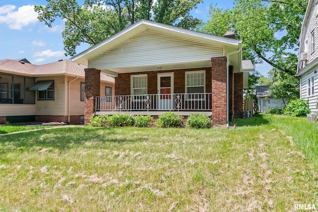 view of front facade featuring a porch, a front lawn, and brick siding