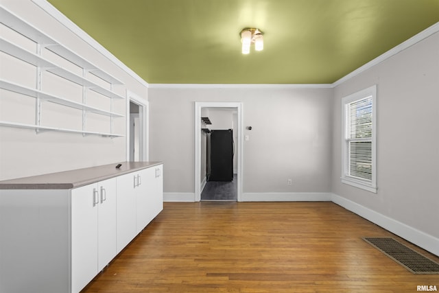 empty room featuring ornamental molding, wood finished floors, and baseboards