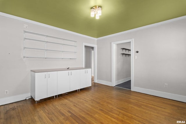 spare room with baseboards, wood finished floors, and ornamental molding