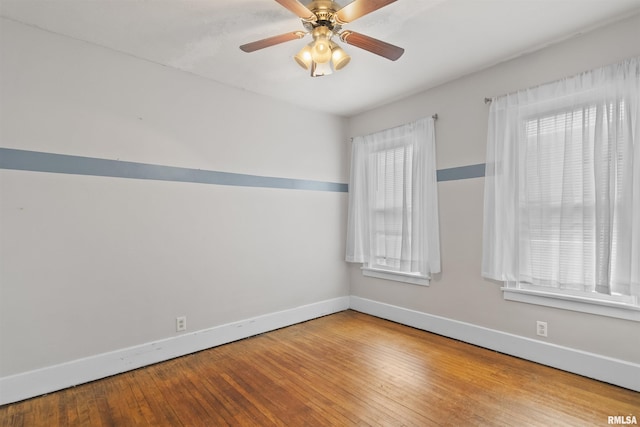 spare room featuring baseboards, hardwood / wood-style floors, and a ceiling fan