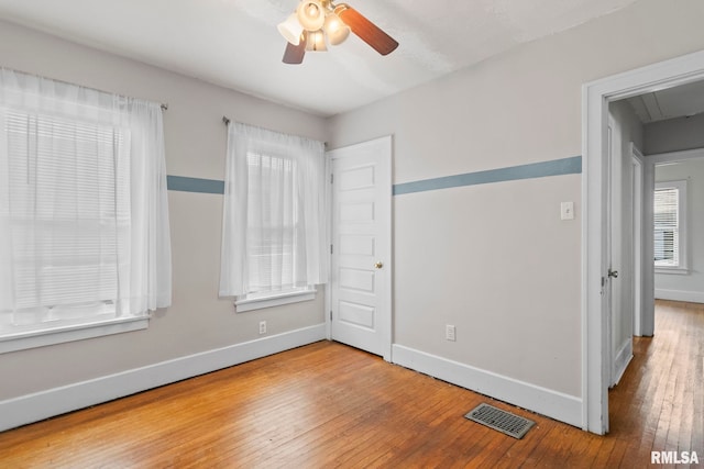 unfurnished bedroom featuring hardwood / wood-style floors, attic access, and baseboards
