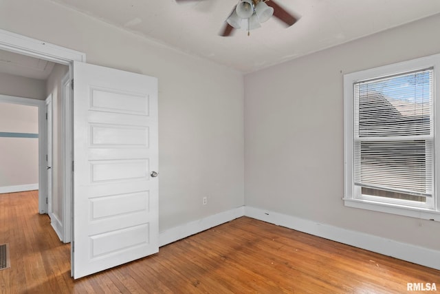 empty room with a ceiling fan, hardwood / wood-style floors, and baseboards