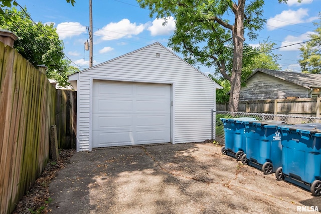 detached garage featuring asphalt driveway and fence