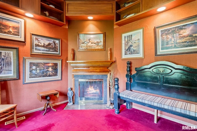 sitting room featuring a fireplace with flush hearth, baseboards, and carpet floors