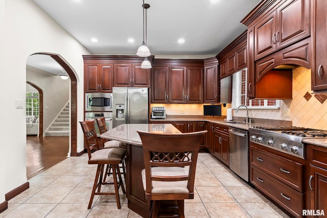 kitchen featuring stainless steel appliances, arched walkways, a sink, light tile patterned floors, and backsplash