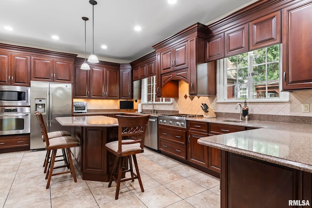 kitchen with appliances with stainless steel finishes, a sink, tasteful backsplash, a breakfast bar area, and recessed lighting