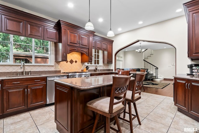 kitchen with stainless steel dishwasher, a sink, arched walkways, recessed lighting, and decorative backsplash
