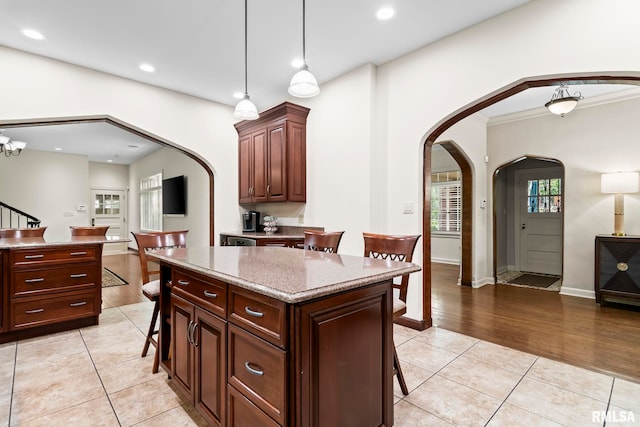 kitchen with arched walkways, a breakfast bar area, light tile patterned flooring, recessed lighting, and baseboards