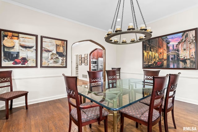 dining space with a chandelier, arched walkways, crown molding, wood finished floors, and baseboards