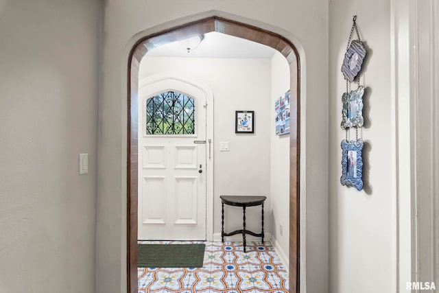 entrance foyer featuring baseboards and arched walkways