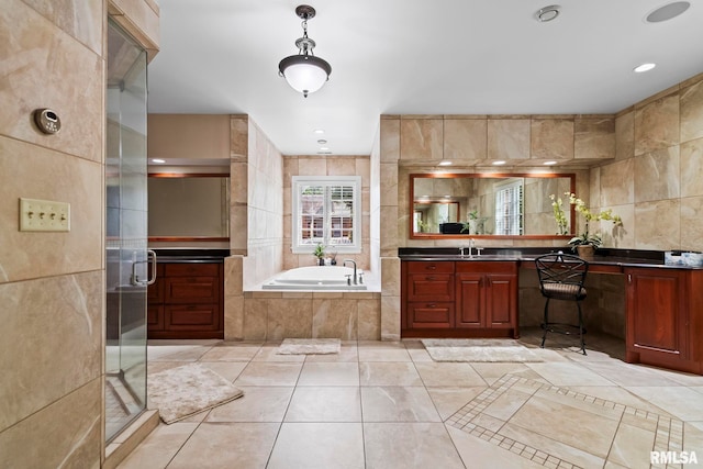 bathroom featuring a stall shower, tile walls, a garden tub, vanity, and tile patterned flooring
