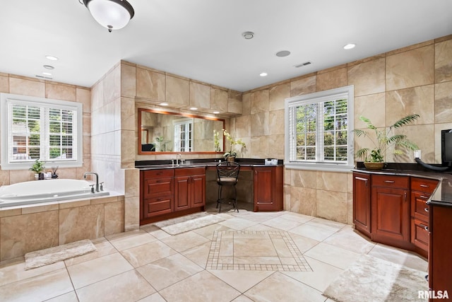 full bathroom featuring tile walls, healthy amount of natural light, vanity, a bath, and tile patterned flooring