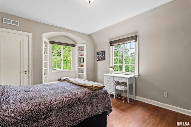 bedroom featuring baseboards, wood finished floors, and multiple windows