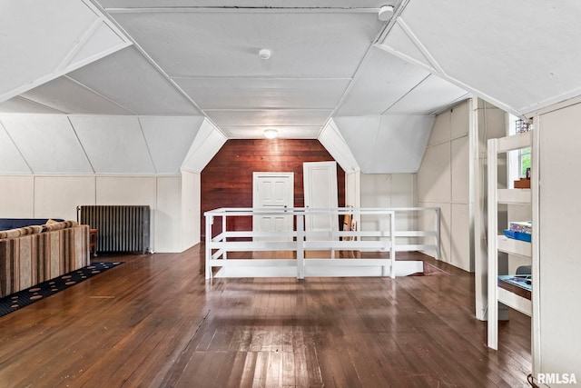 additional living space featuring wood-type flooring, wood walls, and vaulted ceiling