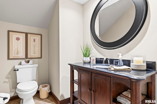 half bath with vanity, toilet, and baseboards