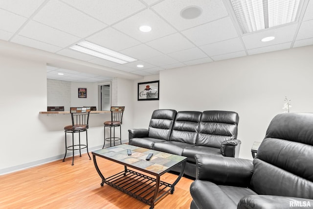 living room featuring light wood-style flooring, a drop ceiling, baseboards, and recessed lighting