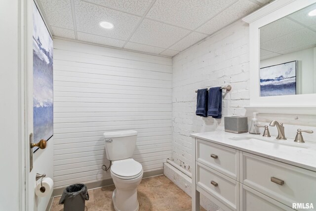 bathroom featuring a paneled ceiling, toilet, and vanity