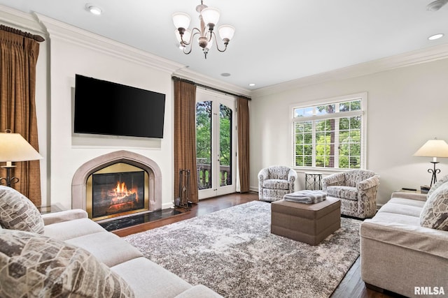 living area featuring crown molding, wood finished floors, a chandelier, a glass covered fireplace, and recessed lighting