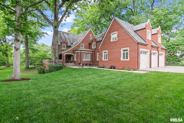 view of front of property featuring driveway, a front yard, brick siding, and a patio area