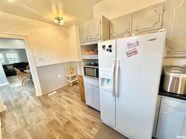 103 N Ohio Ave, Abingdon, IL 61410 - kitchen featuring white fridge with ice dispenser, stainless steel microwave, wainscoting, and light wood-style flooring