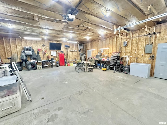 103 N Ohio Ave, Abingdon, IL 61410 - garage featuring a workshop area, fridge, electric panel, and a garage door opener