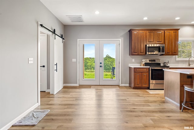 142 Oak Rd, Harrisburg, IL 62946 - kitchen featuring appliances with stainless steel finishes, a barn door, french doors, light countertops, and light wood-style flooring