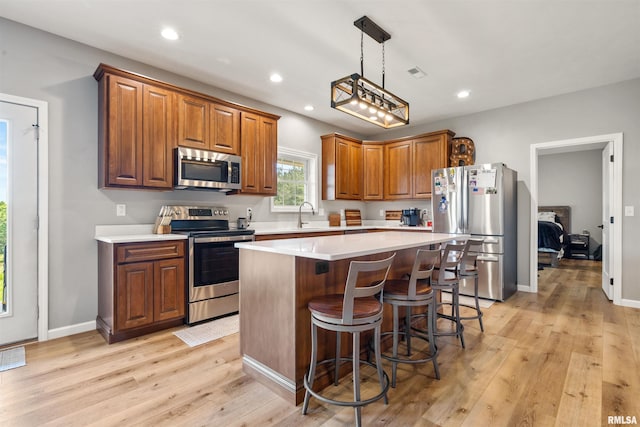 142 Oak Rd, Harrisburg, IL 62946 - kitchen with appliances with stainless steel finishes, light wood-style flooring, a kitchen island, light countertops, and brown cabinets