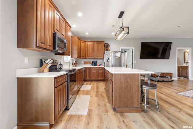 142 Oak Rd, Harrisburg, IL 62946 - kitchen with stainless steel appliances, a sink, light wood-style flooring, a kitchen breakfast bar, and a kitchen island