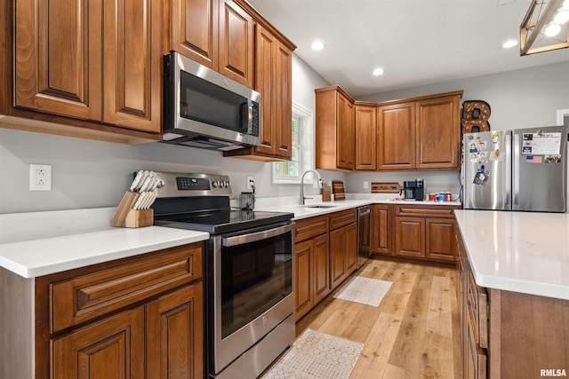 142 Oak Rd, Harrisburg, IL 62946 - kitchen with appliances with stainless steel finishes, a sink, brown cabinets, light wood-type flooring, and recessed lighting
