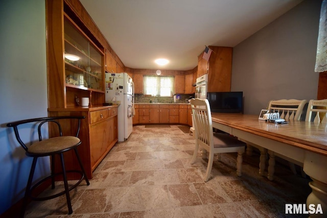 7059 Midway Rd, Metropolis, IL 62960 - kitchen with white appliances, light stone finish flooring, a sink, brown cabinetry, and backsplash