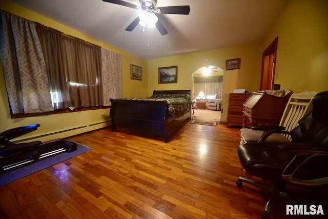 7059 Midway Rd, Metropolis, IL 62960 - bedroom with arched walkways, wood finished floors, a baseboard heating unit, and a ceiling fan