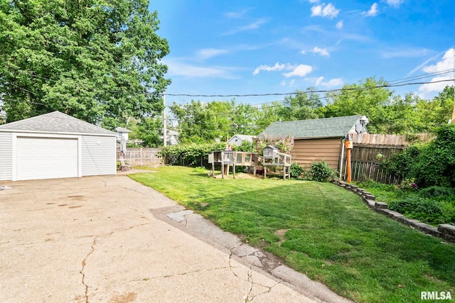 view of yard featuring an outbuilding, concrete driveway, and a detached garage