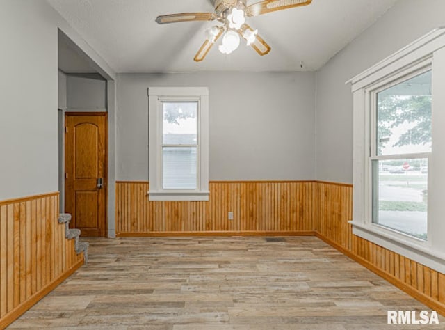 1507 4th St, Lincoln, IL 62656 - unfurnished room with a wainscoted wall, light wood-style flooring, plenty of natural light, a ceiling fan, and wood walls
