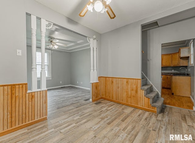 1507 4th St, Lincoln, IL 62656 - unfurnished living room with ceiling fan, light wood-type flooring, a wainscoted wall, decorative columns, and a sink