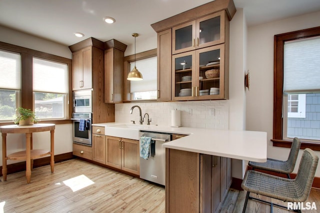 321 S 23rd St, Quincy, IL 62301 - kitchen with stainless steel appliances, a peninsula, light wood-type flooring, a sink, and tasteful backsplash