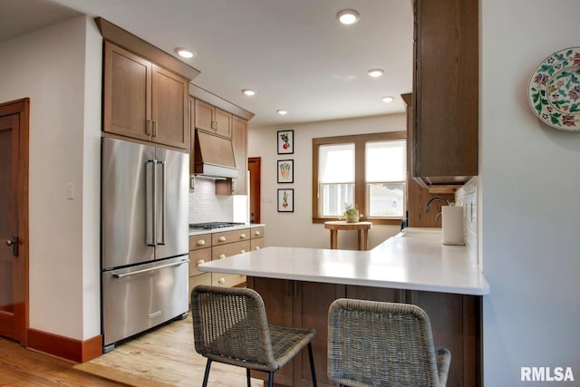 321 S 23rd St, Quincy, IL 62301 - kitchen with stainless steel appliances, custom exhaust hood, light wood-type flooring, decorative backsplash, and light countertops