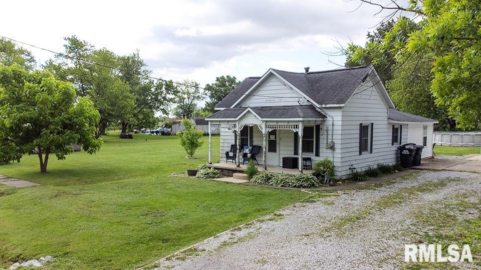 607 E 3rd St, Kinmundy, IL 62854 - bungalow-style house featuring a porch, roof with shingles, gravel driveway, and a front lawn