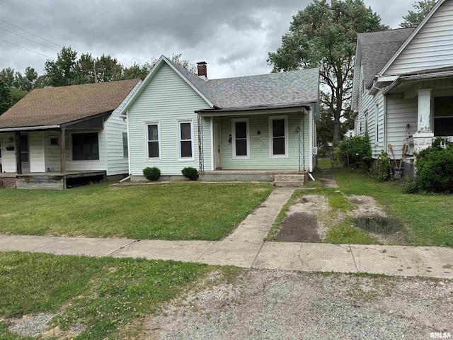 1248 N Ledlie Ave, Springfield, IL 62702 - view of front of house featuring covered porch, a chimney, a front lawn, a shingled roof, and driveway