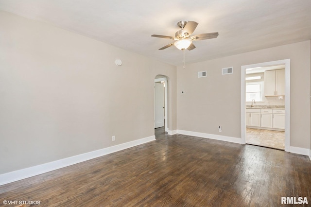 2428 S 8th St, Springfield, IL 62703 - empty room featuring arched walkways, dark wood finished floors, a ceiling fan, baseboards, and a sink